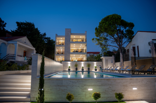 Front exterior night view of Bumblebee apartments in Novalja with illuminated pool and terrace